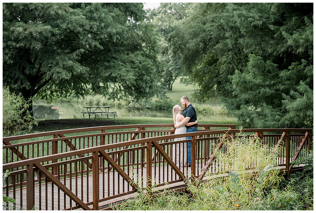 couple standing on bridge shawnee mission park engagement